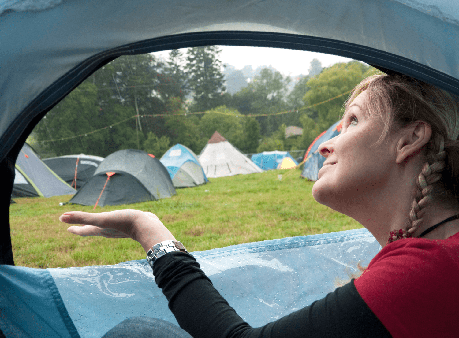 Camper in tent checking for raindrops outside