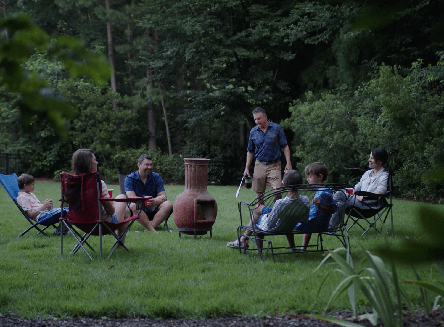 Crowd gathered around outdoor stove, charcoal pit in backyard