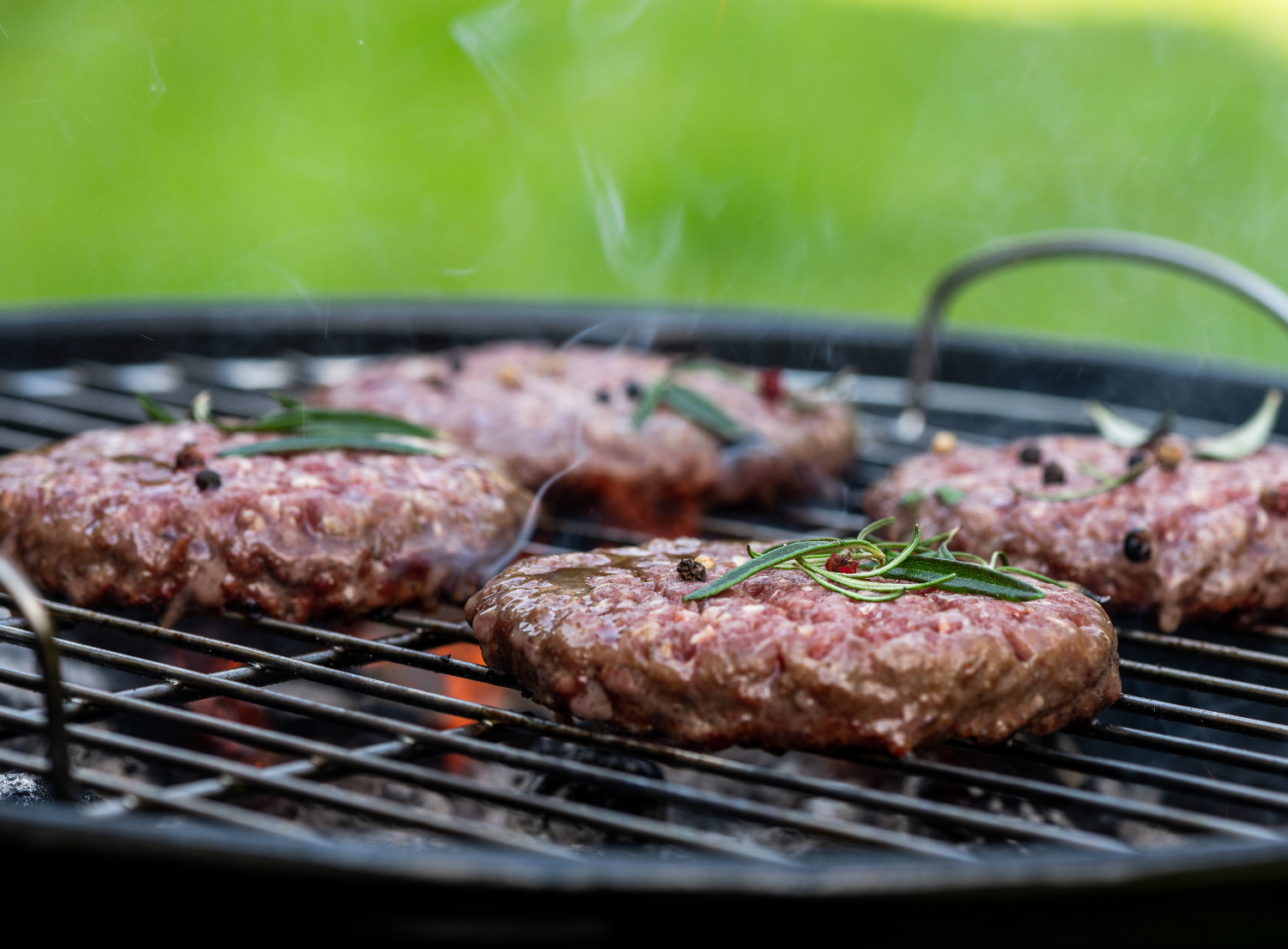 Hamburgers cooking on a charcoal grill
