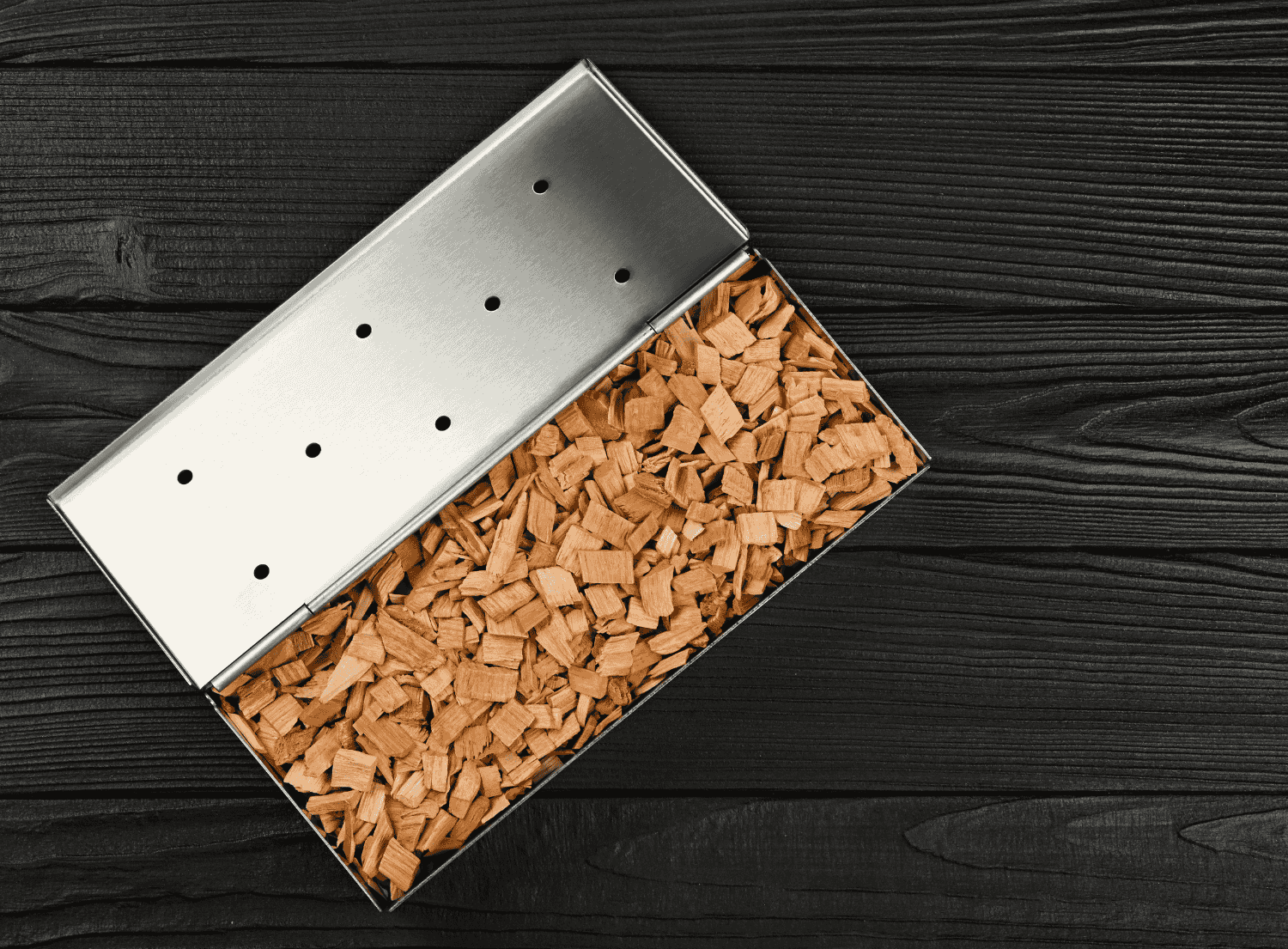steel smoker box filled with flavored wood chips