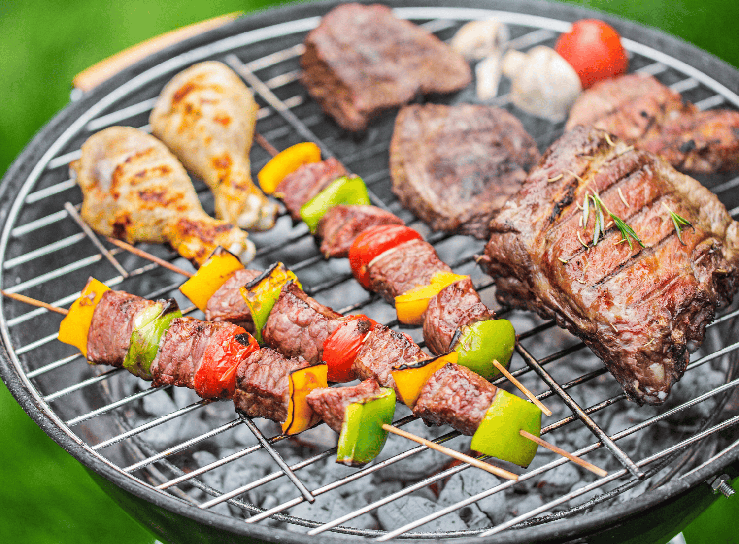 meat and vegetables being grilled on a charcoal grill