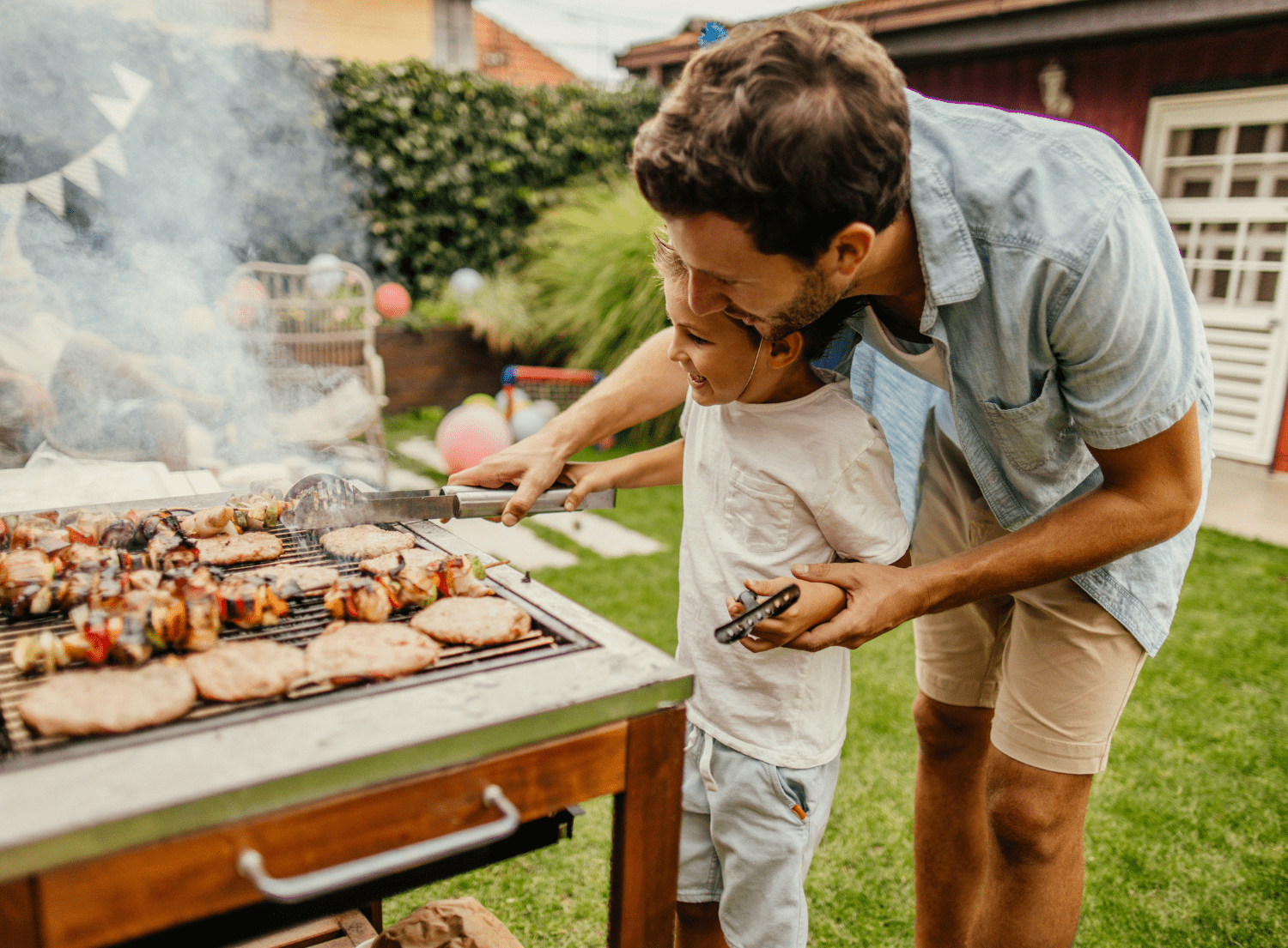 A father and son grilling meat over a open grill