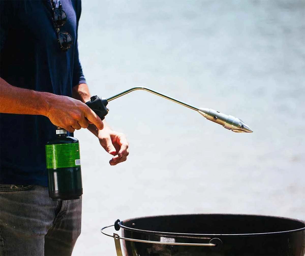 Man lighting charcoal grill at campfire site