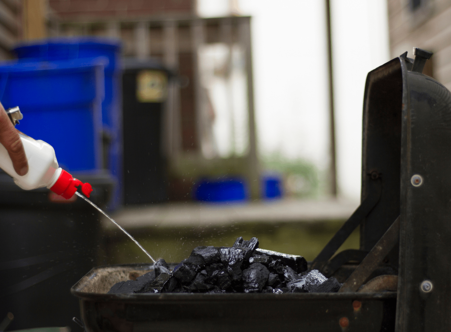 lighter fluid being poured on charcoal grill
