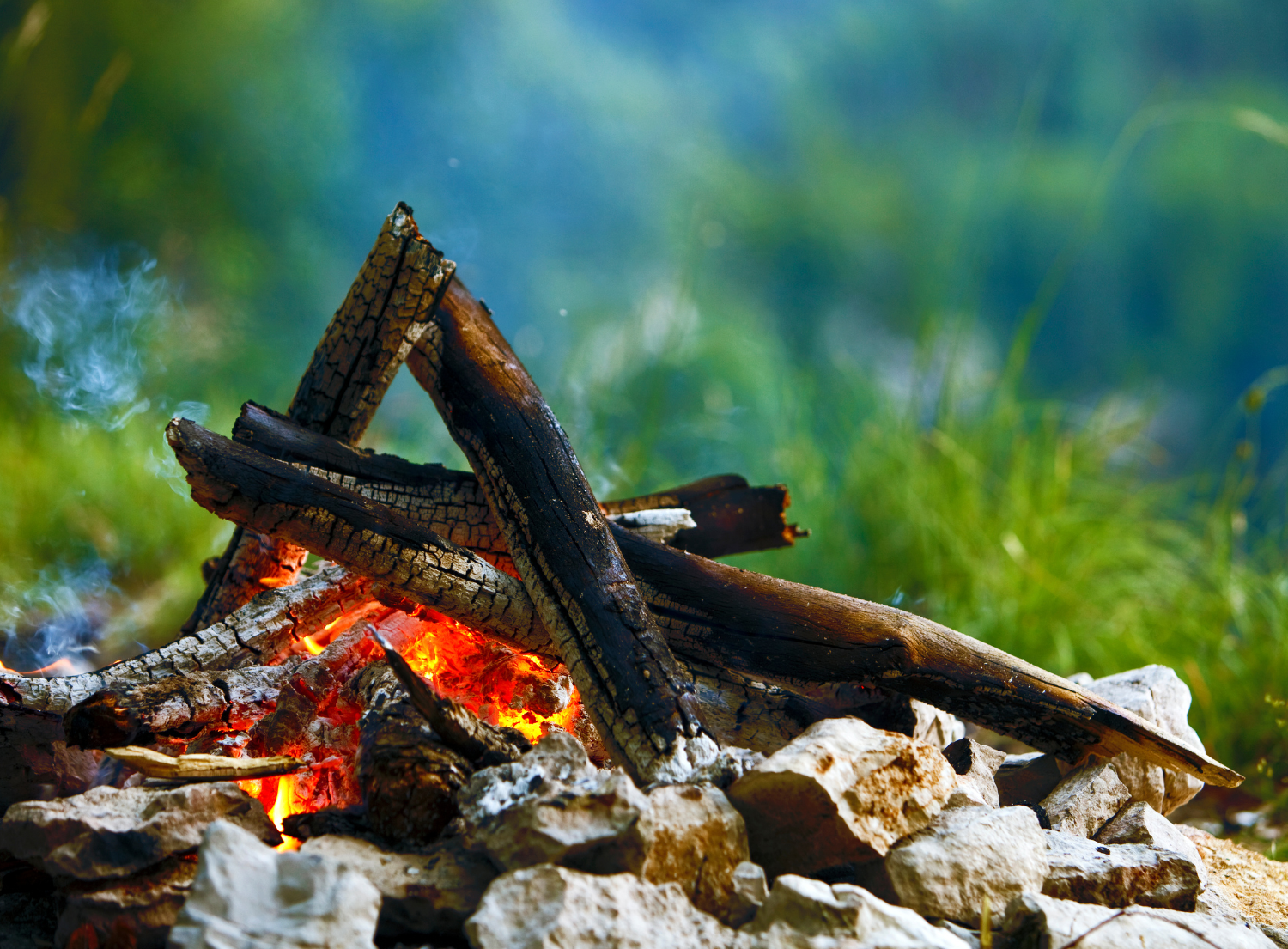 stacked firewood burning in a campfire