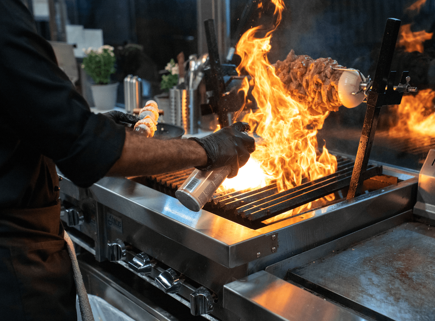 a man grilling meat indoors with a large flame